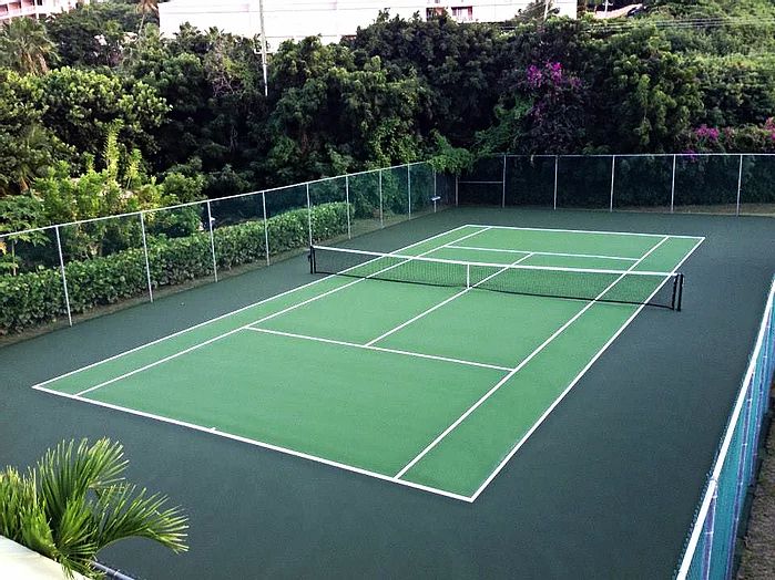 Green tennis court with white line markings